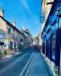 a person walking down a street in an old town at Luxury Modern Cotswold Cottage in Stow on the Wold