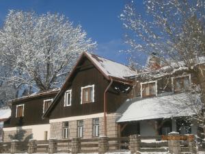 a house covered in snow with a fence at Horská chata Roubenka in Strážné