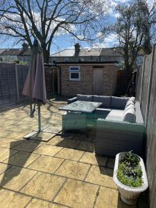 a patio with a couch and an umbrella and a table at Amazing Studio Apartment in North East London in London