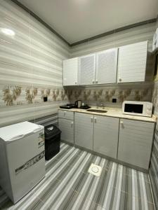 eine Küche mit weißen Schränken und einer Mikrowelle in der Unterkunft قمم بارك Qimam Park Hotel 4 in Abha