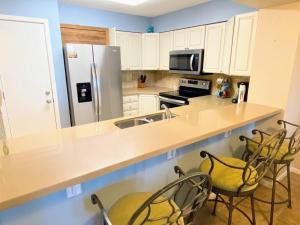 eine Küche mit einer Theke mit Stühlen und einem Kühlschrank in der Unterkunft Summer House 109 - Beach and Pool Walkout - 30 Seconds to Sand in Isle of Palms