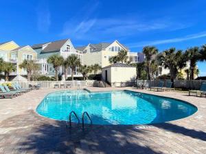 ein Swimmingpool mit blauem Wasser vor Häusern in der Unterkunft Summer House 109 - Beach and Pool Walkout - 30 Seconds to Sand in Isle of Palms