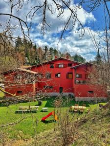 un granero rojo con mesas de picnic delante en Apartaments Cel i Fusta, en Camprodon