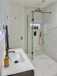 La salle de bains blanche est pourvue d'une douche et d'un lavabo. dans l'établissement Heather Mere Cottage, Bowness-on-Windermere, à Bowness-on-Windermere