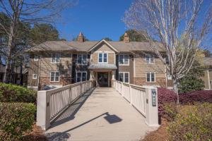 une grande maison avec une passerelle en bois devant elle dans l'établissement Stunning Reynolds Lake Oconee, à Greensboro