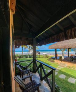 a porch with two chairs and a view of the beach at Anauí Pousada in Porto De Galinhas