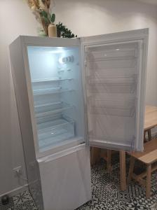 una nevera vacía con la puerta abierta junto a una mesa en Sweet Home en Mulhouse