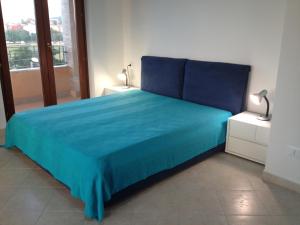 un letto blu in una stanza con finestra di Regina Apartments ad Alghero