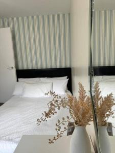 a bedroom with a bed with a vase on a table at Abbey Wood Luxurious Flat. in Abbey Wood