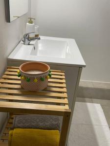 La salle de bains est pourvue d'un lavabo et d'un bol sur un banc en bois. dans l'établissement Les Clés du Bonheur, Entre Mer & Montagne, à Trois Bassins