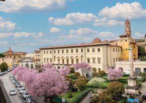 a large building with purple trees in front of a street at Ludyta House in centro Arezzo in Arezzo