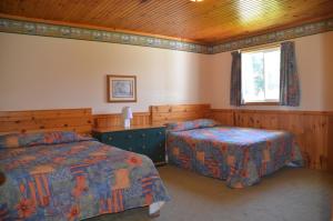 1 dormitorio con 2 camas y ventana en Sundance Cottages, en Cavendish
