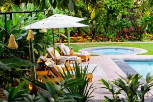 a patio with chairs and an umbrella next to a pool at La Paranera Hotel & Relax in Comala