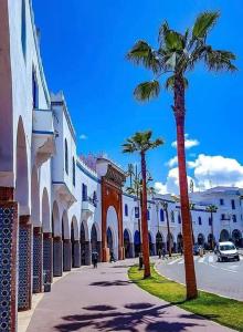 een straat met palmbomen voor een gebouw bij La Maison Haute Larache Morocco in Larache