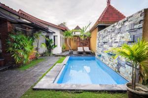 a swimming pool in front of a house at The Janan Villa in Sanur
