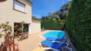 a villa with a swimming pool and blue lounge chairs at Villa Pals Carles Piscina in Pals
