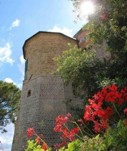 ein Backsteingebäude mit roten Blumen davor in der Unterkunft Castello ala Lucia in Monte Roberto