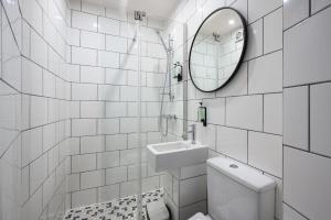 a white tiled bathroom with a sink and a mirror at Cosy City Centre First Floor Family Room in Edinburgh
