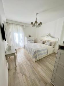Habitación blanca con cama y lámpara de araña. en Maison Mele Ischia en Isquia