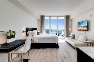 a bedroom with a bed and a desk and a couch at Ocean View Balcony steps from Restaurants, Peacock Park & Marina in Miami