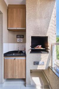 a kitchen with a sink and a fireplace at 2 Quartos com ar, piscina, sacada Gourmet a 1 km da praia Grande in Ubatuba