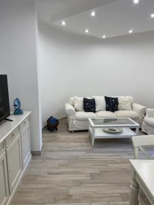 ein weißes Wohnzimmer mit einem Sofa und einem TV in der Unterkunft Maison Mele Ischia in Ischia