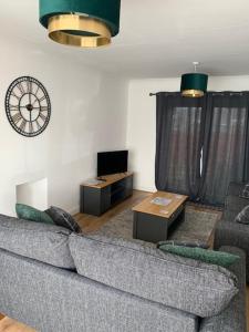 a living room with a couch and a clock on the wall at Plum Tree Corner in Chapel Saint Leonards