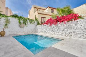 basen przed białą ścianą z różowymi kwiatami w obiekcie Pintada Apartment in Nerja by Solaga Holiday Homes w mieście Nerja