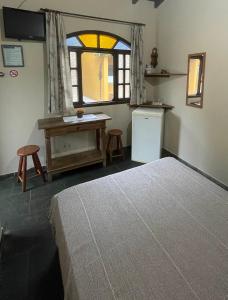 a bedroom with a bed and a desk and a window at Chalés Água de Coco in Boicucanga