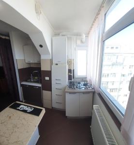 a small kitchen with white cabinets and a window at Blue Sky Apartament in Constanţa