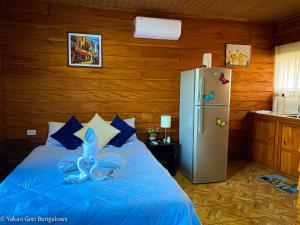 Schlafzimmer mit einem blauen Bett und einem Kühlschrank in der Unterkunft Bungalows Yakari Grei in San Ramón