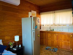 La cocina está equipada con nevera blanca y armarios de madera. en Bungalows Yakari Grei en San Ramón