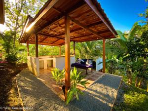 a wooden pergola with a chair on a patio at Bungalows Yakari Grei in San Ramón