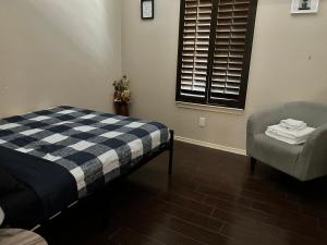 a bedroom with a bed and a chair and a window at Hidden Gem Cozy Home MiCasa TuCasa in El Paso