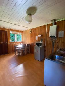 cocina y comedor con mesa y nevera en Bosque Patagonico Cabañas y Camping, en Hornopirén