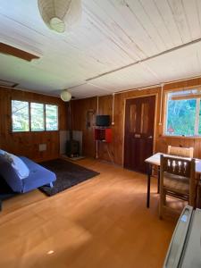 a living room with a bed and a table in it at Bosque Patagonico Cabañas y Camping in Hornopiren