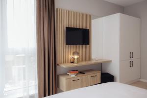 a bedroom with a bed and a dresser with a television at ZEN Garden Apartments in Cluj-Napoca