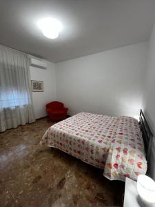 a bedroom with a bed and a red chair at Appartamento Nonna Carmela in Pescara