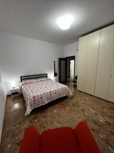 a bedroom with a bed and a red couch at Appartamento Nonna Carmela in Pescara
