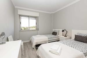 een witte kamer met 2 bedden en een raam bij Cozy Apartment With Sea View in Estoril in Estoril