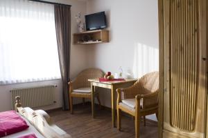 a room with a table and chairs and a bed at Pension Möser in Lennestadt