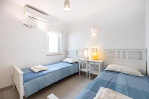 1 Schlafzimmer mit 2 Betten, einem Schreibtisch und einem Fenster in der Unterkunft CoolHouses Algarve Luz, 3 Bed townhouse, lovely sea views, village centre, Casa Limoeiro 54LBC in Luz