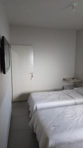 two beds in a white room with a tv at HOTEL ITAVERÁ BRASIL in Presidente Prudente