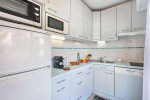 Biała kuchnia z białymi szafkami i kuchenką mikrofalową w obiekcie Forville - AzuRenting Conciergerie -centre ville w Cannes