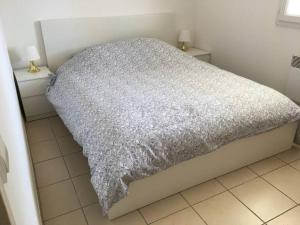 ein Bett mit einer grauen Bettdecke in einem Schlafzimmer in der Unterkunft Lucie in Hyères