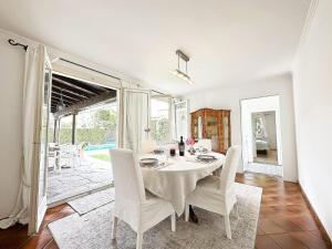uma sala de jantar branca com uma mesa e cadeiras brancas em Casa Via Saleggi 10 em Ascona