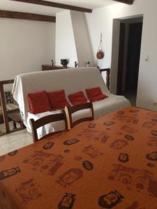 een slaapkamer met een bed en een bank met rode kussens bij Casa Minana in Propriano