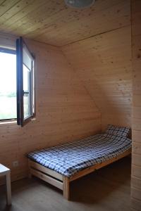a bed in a wooden room with a window at Marco in Sarbinowo