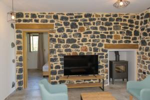 a living room with a stone wall with a flat screen tv at Villas Kozilis - Kozilis Estate in Damnoni
