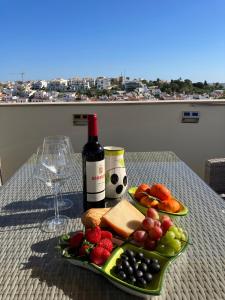 einen Tisch mit einem Obstteller und einer Flasche Wein in der Unterkunft Apartment Beta - 2 Bedrooms, Private Rooftop Patio with Hot Tub, BBQ and View in Ferragudo